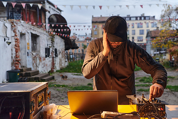 Image showing A young man is entertaining a group of friends in the backyard of his house, becoming their DJ and playing music in a casual outdoor gathering