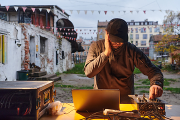 Image showing A young man is entertaining a group of friends in the backyard of his house, becoming their DJ and playing music in a casual outdoor gathering