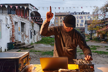 Image showing A young man is entertaining a group of friends in the backyard of his house, becoming their DJ and playing music in a casual outdoor gathering