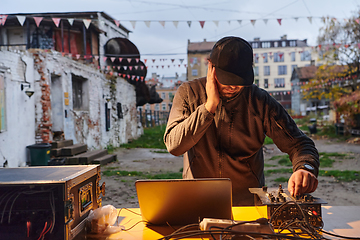 Image showing A young man is entertaining a group of friends in the backyard of his house, becoming their DJ and playing music in a casual outdoor gathering