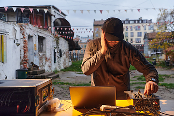 Image showing A young man is entertaining a group of friends in the backyard of his house, becoming their DJ and playing music in a casual outdoor gathering