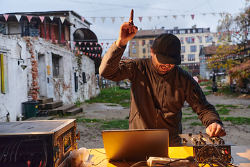 Image showing A young man is entertaining a group of friends in the backyard of his house, becoming their DJ and playing music in a casual outdoor gathering