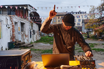 Image showing A young man is entertaining a group of friends in the backyard of his house, becoming their DJ and playing music in a casual outdoor gathering