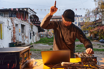 Image showing A young man is entertaining a group of friends in the backyard of his house, becoming their DJ and playing music in a casual outdoor gathering