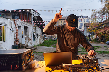 Image showing A young man is entertaining a group of friends in the backyard of his house, becoming their DJ and playing music in a casual outdoor gathering