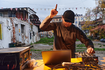 Image showing A young man is entertaining a group of friends in the backyard of his house, becoming their DJ and playing music in a casual outdoor gathering