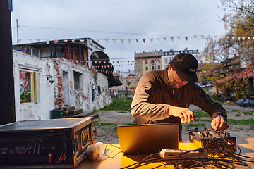 Image showing A young man is entertaining a group of friends in the backyard of his house, becoming their DJ and playing music in a casual outdoor gathering