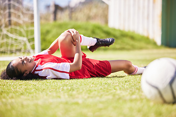 Image showing Injured, pain or injury of a female soccer player lying on a field holding her knee during a match. Hurt woman footballer with a painful leg on the ground in agony having a bad day on the pitch