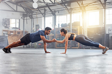 Image showing Active couple holding hands for support in pushup, plank and balance training during fitness, workout and exercise in a gym. Sporty, strong and fit athletes helping with bodyweight wellness challenge