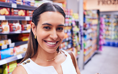 Image showing Shopping, groceries and consumerism with a young woman in a grocery store, retail shop or supermarket aisle. Closeup portrait of a female standing with packed shelves of consumables in the background