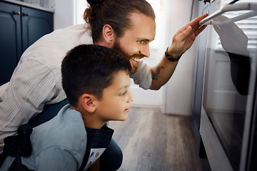 Image showing Father and son baking cake together in kitchen at home, bonding and waiting by oven stove. Loving, adoptive single parent taking care of curious little boy learning to bake or cook.