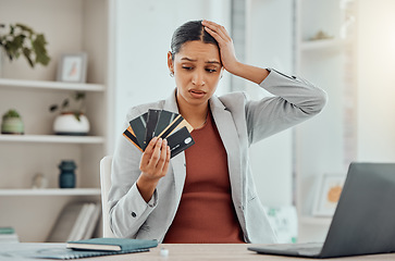 Image showing Financial stress, concerned and frustrated woman holding bank cards in her hand at her desk. Business female worried about economic decisions, credit interest or loan and debt in money crisis.