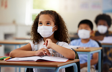 Image showing School student with covid learning in class, wearing mask to protect from virus and looking concentrated on education in classroom. Little girl sitting at desk, studying and listening during pandemic