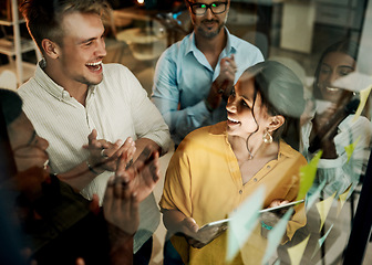 Image showing Successful business team clapping and cheering after planning a project on a glass wall in a office. Group of smiling businesspeople sharing ideas and strategies together in a creative startup agency