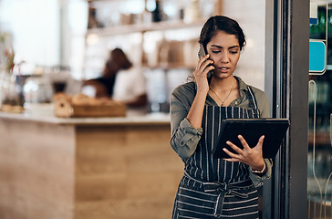 Image showing Female cafe business owner using phone talking, ordering and reading on tablet in her store. Serious businesswoman, entrepreneur or employee standing in a coffee shop preparing online grocery order.