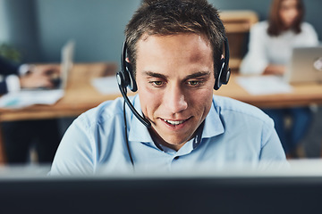 Image showing Closeup of a young male call center agent consulting and giving support while working in a busy office. Face of a man and helpdesk worker or phone operator having a conversation