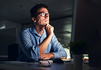 Image showing Businessman thinking of ideas in front of a computer while working late in an office at night. Hard Working entrepreneur sending emails, online research and reports trying to reach deadline overtime