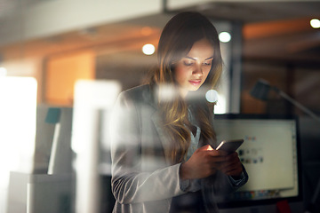 Image showing Business woman reading message on phone, checking notifications and browsing online for a cab after working late in dark office. Corporate professional, employee and worker scrolling on social media