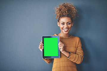 Image showing African female holding green screen tablet copyspace. Cute, attractive and smiling young afro woman standing and showing a mobile device.Happy, cheerful and ethnic woman after buying new app.