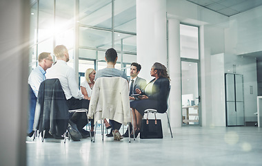 Image showing Group of diverse coworkers talking together while sitting in a circle in an office. Employees having a team business meeting discussion for counseling or support group at a corporate workplace.