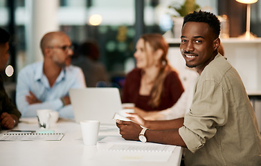 Image showing Proud, happy and smiling young businessman holding digital tablet during business meeting. Ambitious young businessperson with team or colleagues in office, sitting in a modern boardroom.