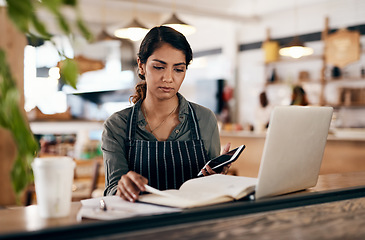 Image showing Cafe owner with laptop, phone and book checking online order, searching available bookings and preparing takeaway deliveries coffee shop. Serious local restaurant entrepreneur pricing a menu on tech