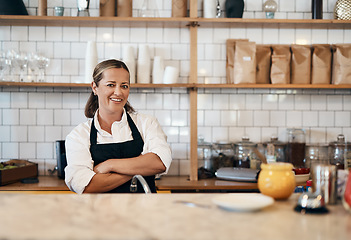 Image showing Business owner, barista standing with arms crossed, looking confident and proud while working at a restaurant. Cafe worker, employee and entrepreneur smiling, giving service and leading a coffee shop