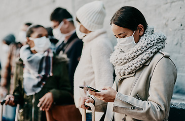 Image showing People or tourists traveling during covid and standing in line at a public travel facility wearing protective masks. Woman in a queue reading social media news about coronavirus pandemic on her phone