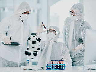 Image showing Group of doctors and scientists conducting medical research on viruses dressed in hazmat suits, for coronavirus cure in the lab. Researchers conducting experiments and examining test tube