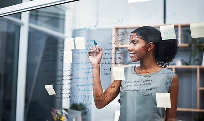 Image showing Female leadership and marketing professional brainstorming innovation ideas, writing on transparent board with sticky notes in office. Young entrepreneur planning business mission and strategy.