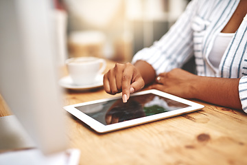 Image showing Female african hand using a tablet at a desk doing office work. Closeup of a professional woman browsing on social media while having a cup of tea or coffee. Businesswoman doing research online.