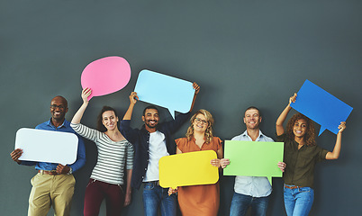 Image showing Smiling casual team of diverse people holding opinion speech bubbles, to voice their important communication message. Creative group standing with colorful copyspace sign boards together in a row