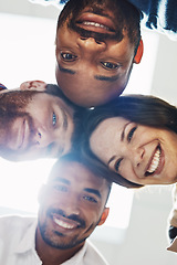 Image showing Portrait of a diverse group of happy office workers from below joining together in a huddle for support and unity with lights in the background. Cheerful motivated colleagues ready for business