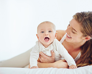 Image showing Loving mother and baby bonding at home, playing while relaxing on a bed together. Happy parent being affectionate with her newborn son, embracing him and sharing precious moments of parenthood