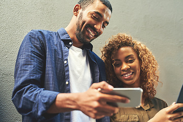 Image showing Smiling young couple looking, laughing and holding phone together showing a funny social media app. Friends sharing a gossip news article post online. Guy looking at internet web content with girl