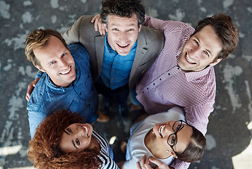 Image showing Cheerful, united and diverse group of young business colleagues in collaboration for corporate trust building. Top view of coworkers looking up, smiling and standing close together.