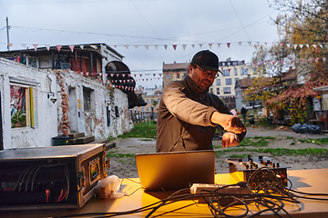 Image showing A young man is entertaining a group of friends in the backyard of his house, becoming their DJ and playing music in a casual outdoor gathering