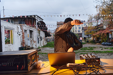 Image showing A young man is entertaining a group of friends in the backyard of his house, becoming their DJ and playing music in a casual outdoor gathering