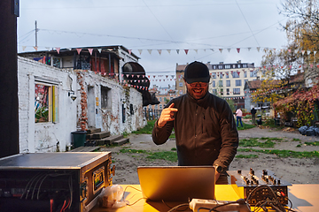 Image showing A young man is entertaining a group of friends in the backyard of his house, becoming their DJ and playing music in a casual outdoor gathering