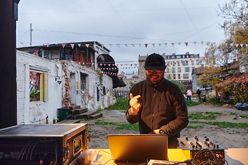 Image showing A young man is entertaining a group of friends in the backyard of his house, becoming their DJ and playing music in a casual outdoor gathering