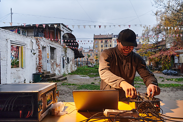 Image showing A young man is entertaining a group of friends in the backyard of his house, becoming their DJ and playing music in a casual outdoor gathering