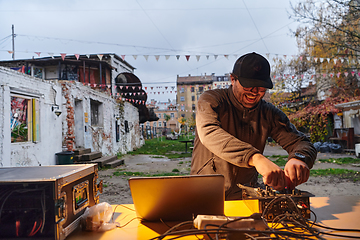 Image showing A young man is entertaining a group of friends in the backyard of his house, becoming their DJ and playing music in a casual outdoor gathering