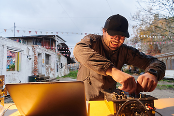 Image showing A young man is entertaining a group of friends in the backyard of his house, becoming their DJ and playing music in a casual outdoor gathering