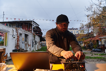 Image showing A young man is entertaining a group of friends in the backyard of his house, becoming their DJ and playing music in a casual outdoor gathering