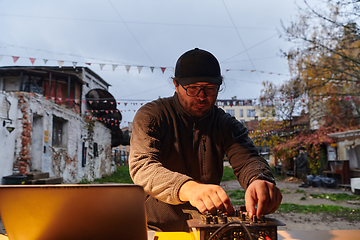 Image showing A young man is entertaining a group of friends in the backyard of his house, becoming their DJ and playing music in a casual outdoor gathering