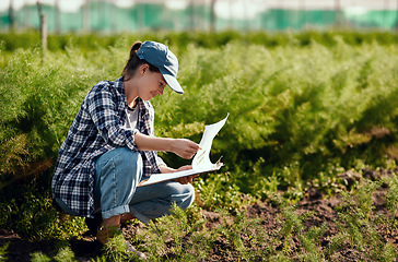 Image showing Young female farmer preparing for harvest while working on her farm field ensuring the organic soil is fresh and sustainable outside. Happy worker reading her clipboard notes to check farming land