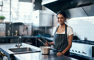 Image showing Cooking, making food and working as a chef in a commercial kitchen with tongs and industrial equipment. Portrait of a female cook preparing a meal for lunch, dinner or supper in a restaurant or cafe