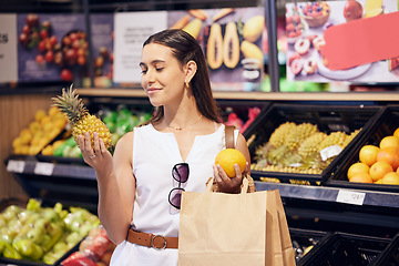 Image showing Shopping, holding and looking at fruit at shop, buying healthy food and examining items at a grocery store. Woman deciding, choosing and picking ripe, fresh and delicious produce at a market