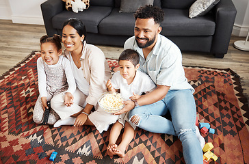 Image showing Happy, bonding family quality time at home with parents watching a movie and having snacks on the floor. Young couple being affectionate with their children and enjoying time together indoors