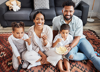 Image showing Watching movie, family bonding and eating popcorn while relaxing in the lounge together at home. Happy, smiling and carefree parents enjoying snack, looking at comedy series, laughing with kids